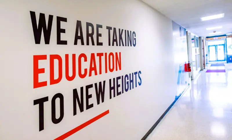 A wall at the College of Education at Illinois that reads "We are Taking Education to New Heights"
